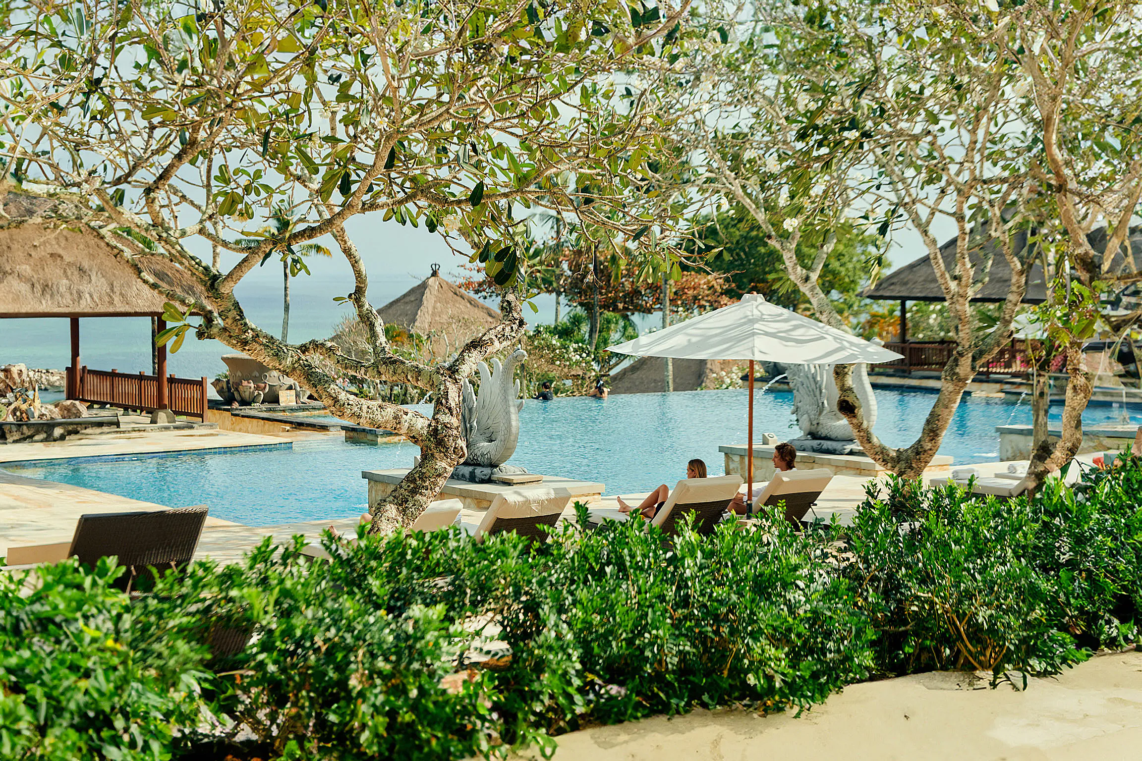 AYANA Resort Bali — oceanfront pool beneath shady trees